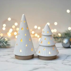 Duas árvores de Natal brancas vazadas, iluminadas por velas LED